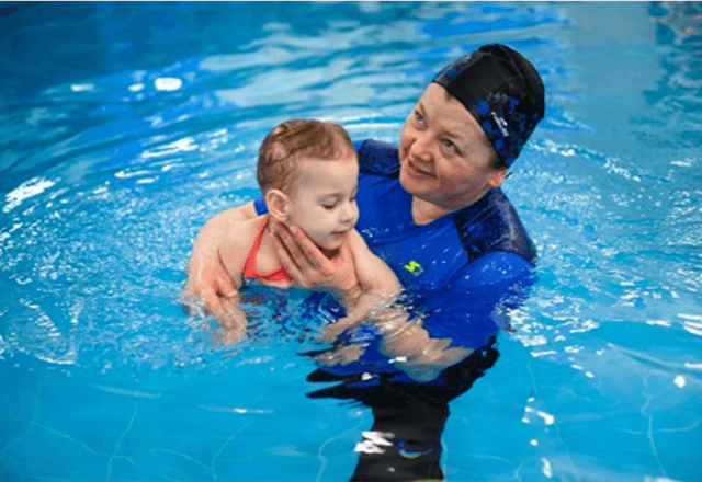 Swim coach Natalia teaching a child to swim